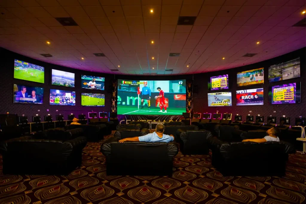 Clientes disfrutando de una transmisión deportiva en la sala de apuestas de Casino Centenario.