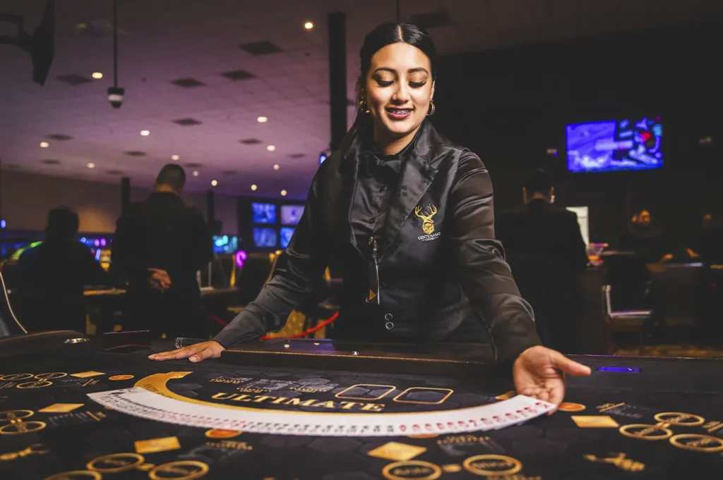 Croupier femenina sonriendo mientras reparte cartas en Casino Centenario.