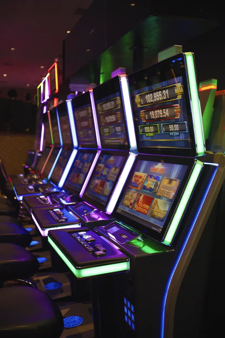 Filas de máquinas tragamonedas iluminadas en el interior de Casino Centenario.