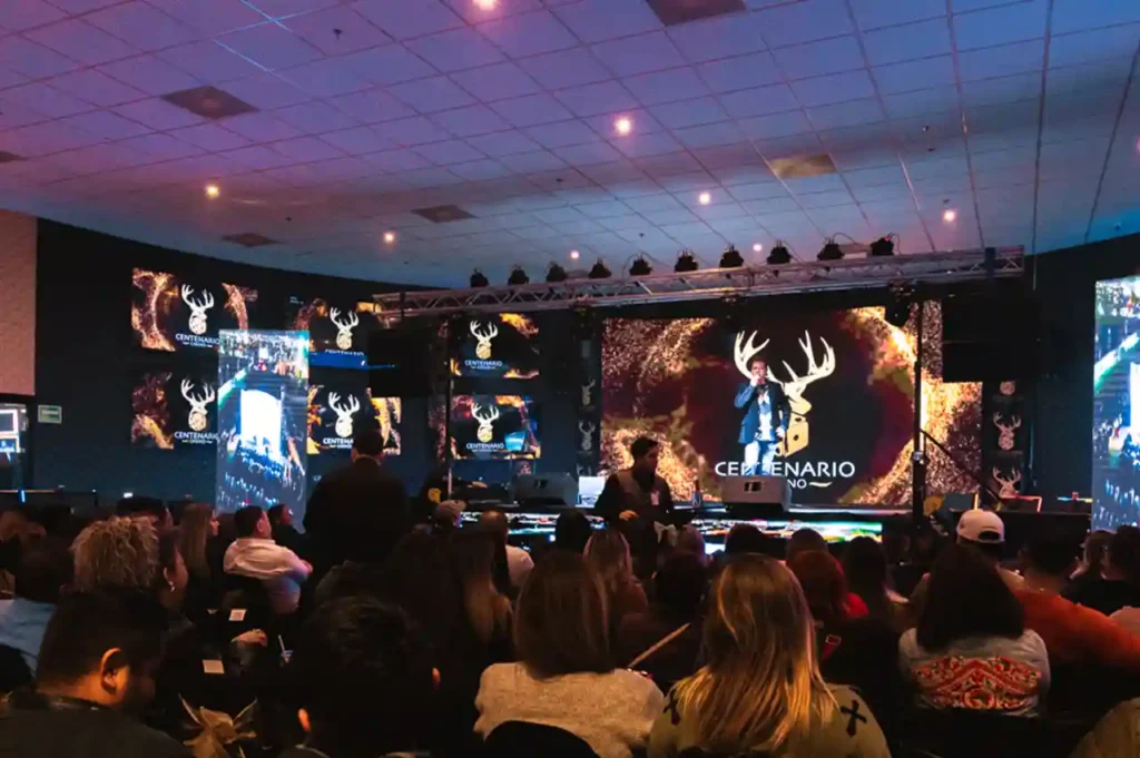 José Luis Zagar en el escenario principal de Casino Centenario, con pantallas gigantes de fondo y un público atento.
